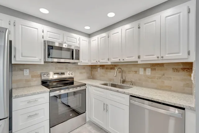 a kitchen with stainless steel appliances granite countertop a sink and a stove