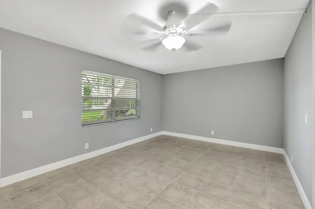 an empty room with windows and fan