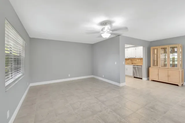 an empty room with windows and chandelier fan