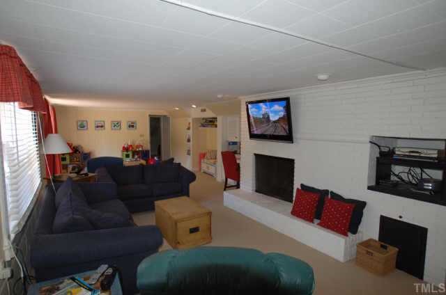3213 Oak Grove Circle Raleigh, NC 27607 - Photo 10 of 10 a living room with furniture a fireplace and a flat screen tv