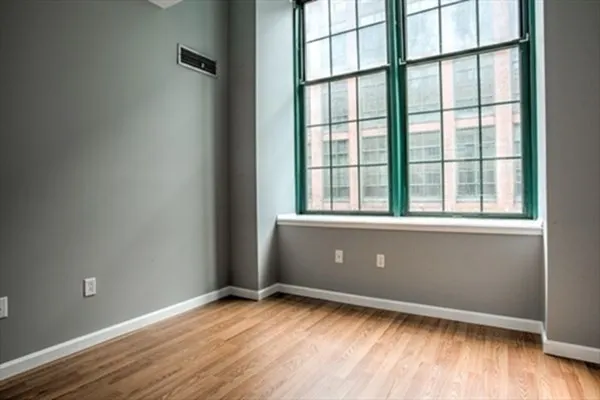an empty room with wooden floor and windows