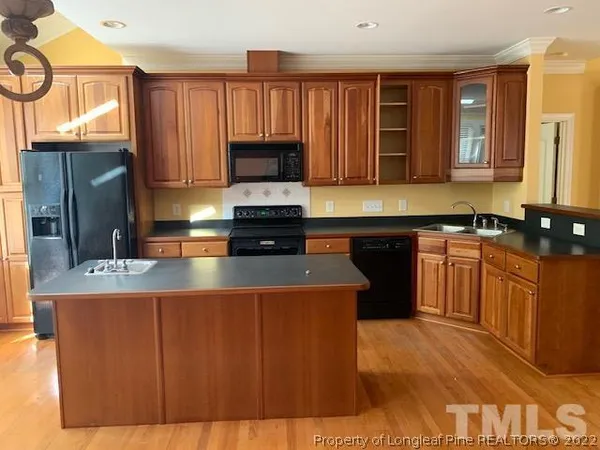 a kitchen with kitchen island granite countertop a sink cabinets and stainless steel appliances