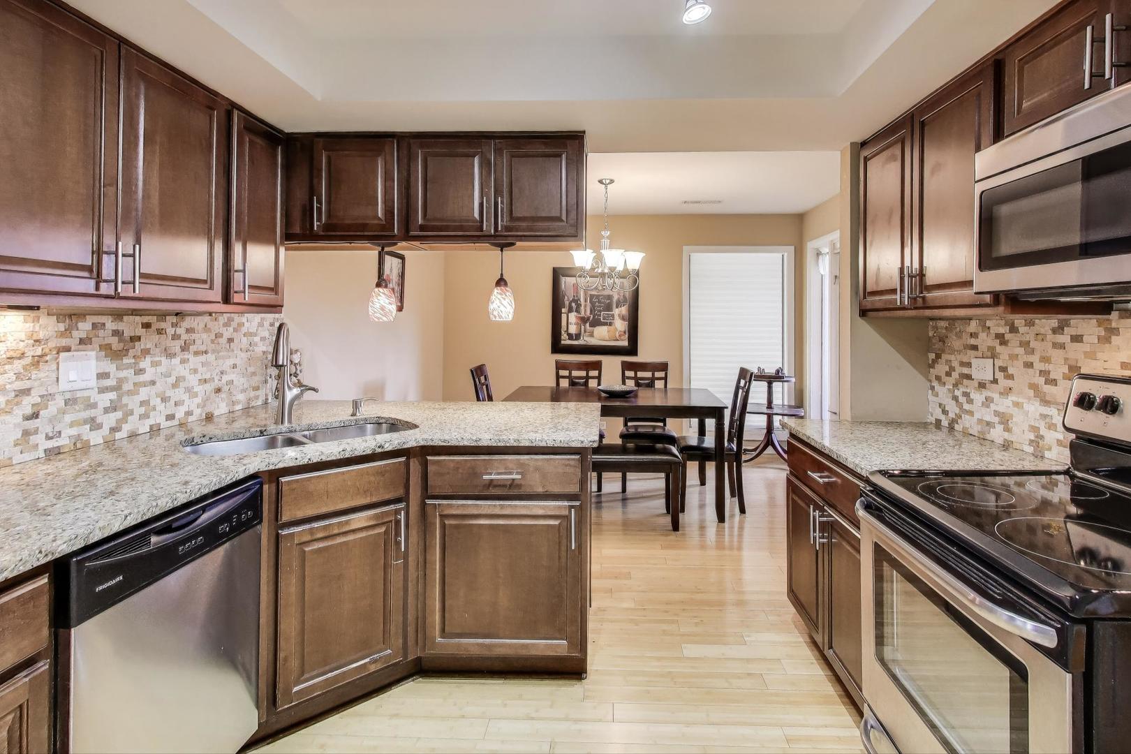 1847 Tanglewood Drive, Unit 2B Glenview, IL 60025 - Photo 2 of 26 a kitchen with stainless steel appliances granite countertop wooden cabinets a stove top oven a sink and dishwasher