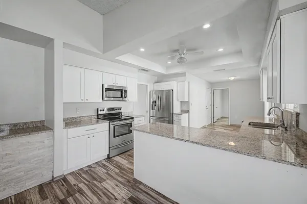 a large kitchen with granite countertop a sink stainless steel appliances and cabinets