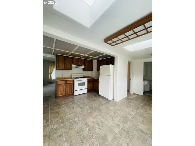 a view of a kitchen with refrigerator and white cabinets