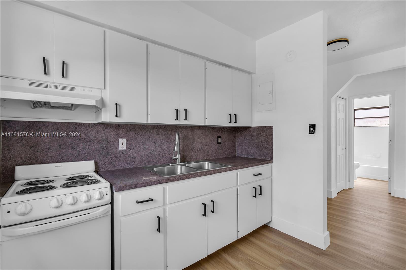 1400 Northwest 55th Street Miami, FL 33142 - Photo 22 of 33 a kitchen with granite countertop white cabinets and white appliances