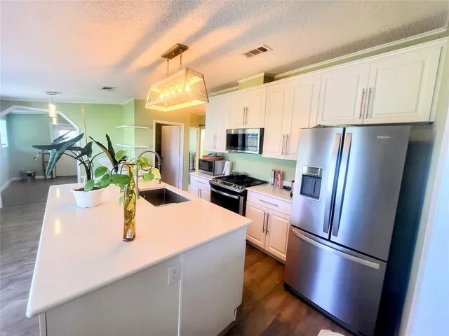 a kitchen with stainless steel appliances a refrigerator a sink a stove a microwave a center island and cabinets