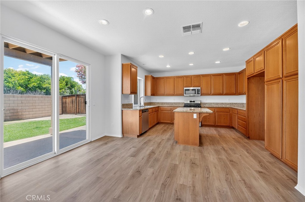 1984 Bronte Road San Jacinto, CA 92583 - Photo 8 of 30 a kitchen with stainless steel appliances granite countertop a refrigerator a sink dishwasher a stove and a microwave oven with wooden floor