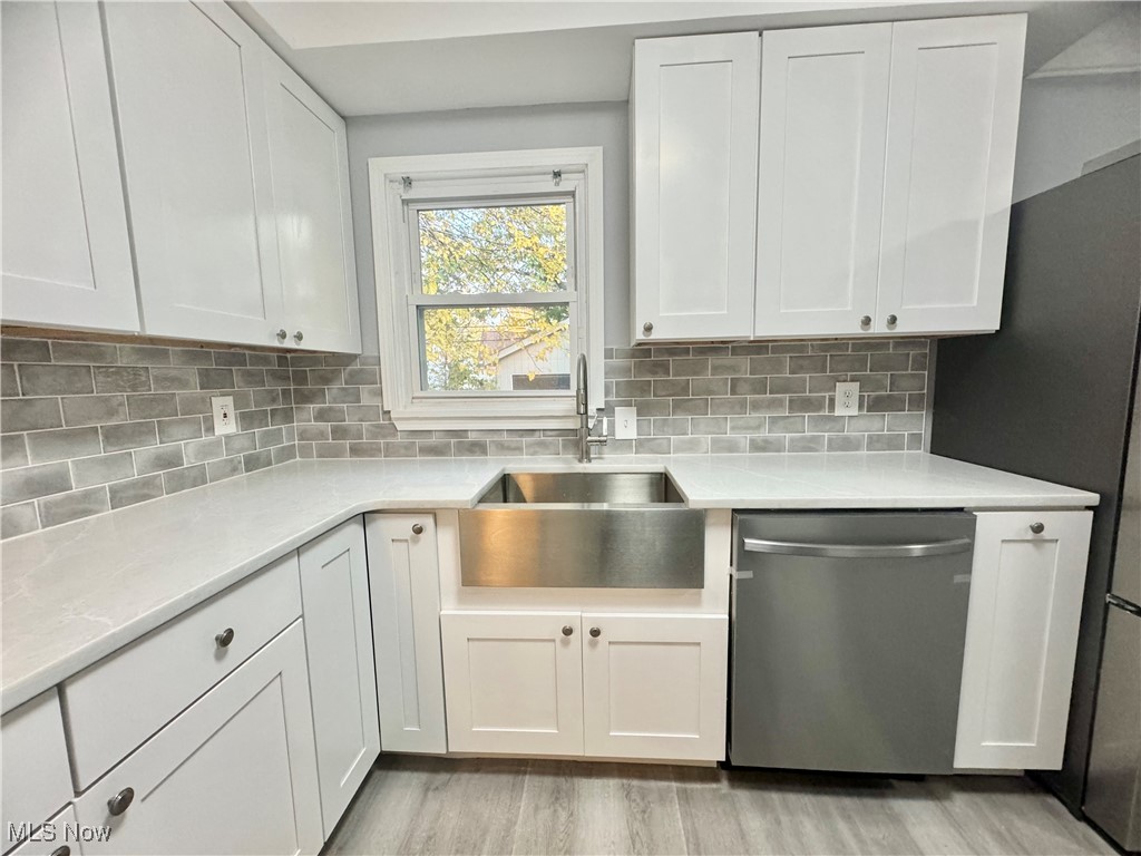 1215 Avondale Road Cleveland, OH 44121 - Photo 5 of 27 Kitchen with stainless steel dishwasher, sink, white cabinets, and light hardwood / wood-style floors