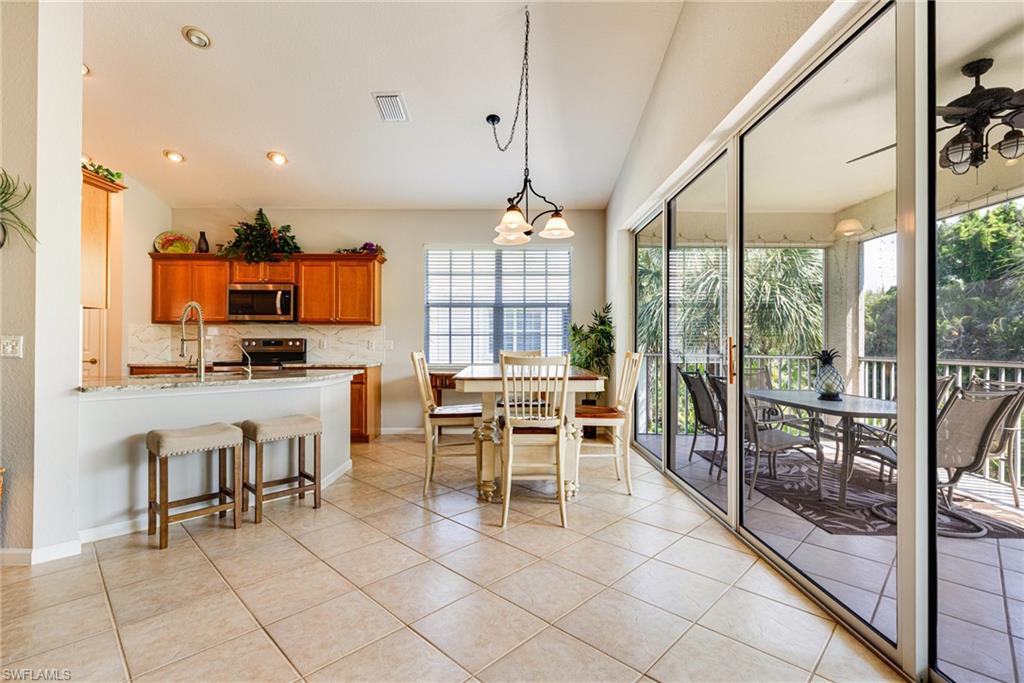 19081 Ridgepoint Drive, Unit 201 Estero, FL 33928 - Photo 26 of 50 a dining hall with stainless steel appliances granite countertop a stove top oven a sink a dining table and chairs with the view of living room