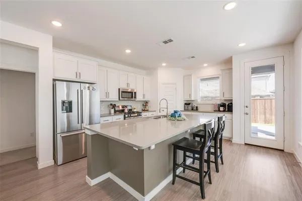 a kitchen with refrigerator a sink and chairs