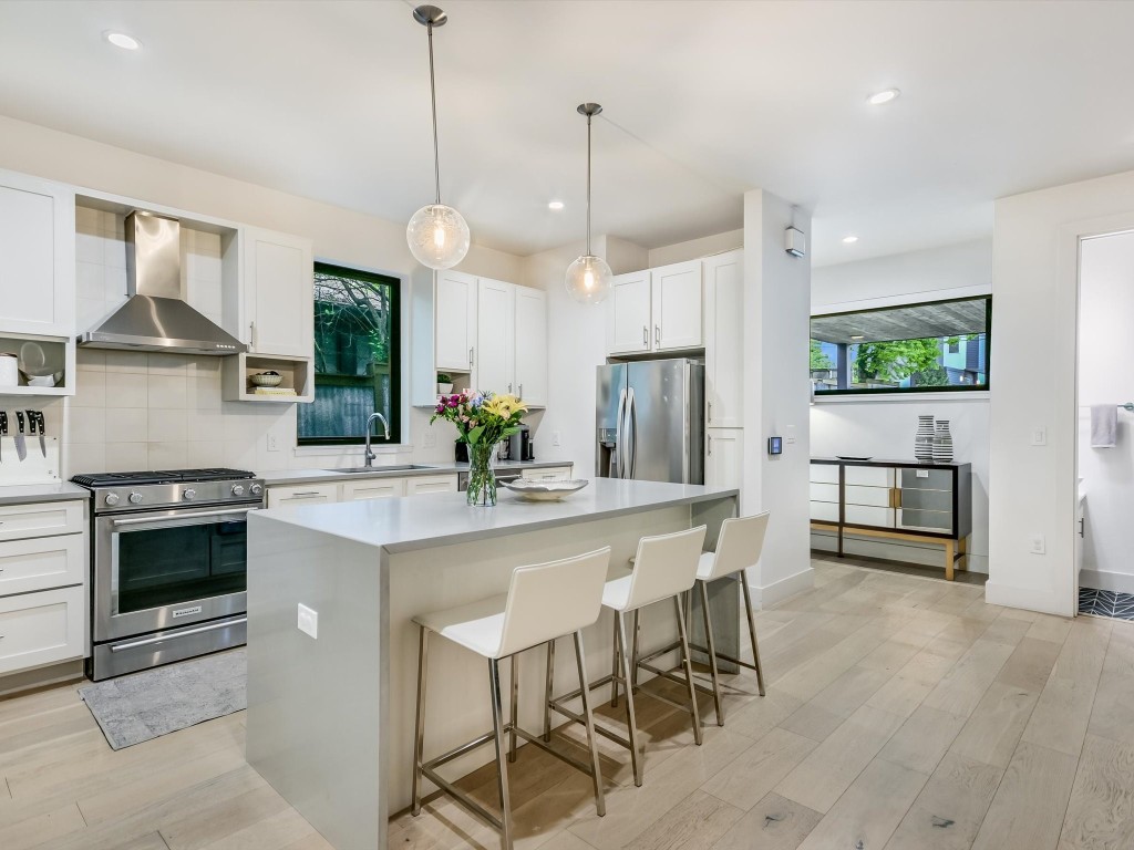 a kitchen with stainless steel appliances a dining table chairs stove and white cabinets