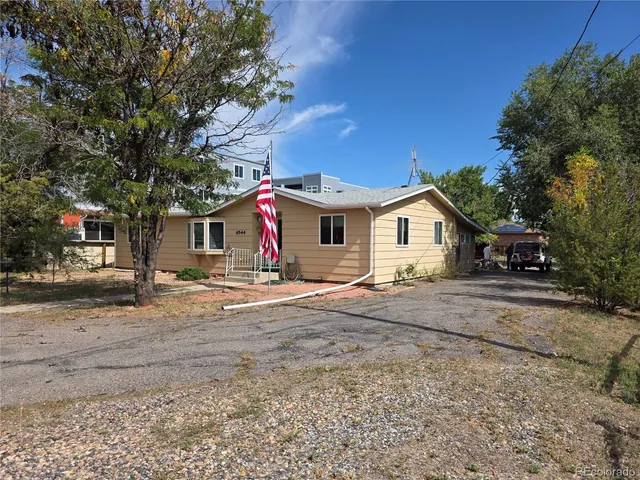 a view of a house with a yard and large tree