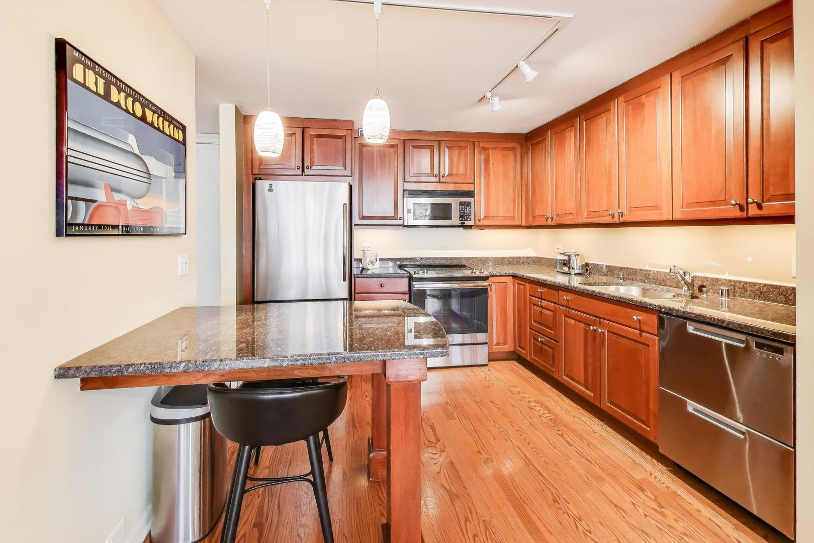 360 East Randolph Street, Unit 1007 Chicago, IL 60601 - Photo 9 of 28 a kitchen with stainless steel appliances kitchen island granite countertop a sink stove and cabinets