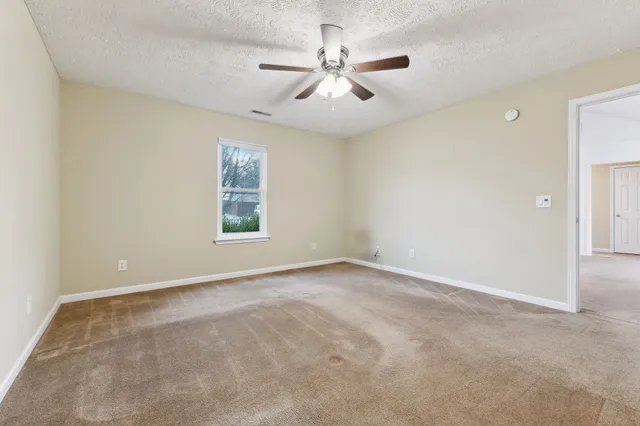 an empty room with windows and fan