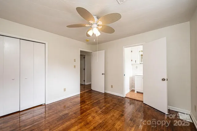 an empty room with wooden floor and ceiling fan