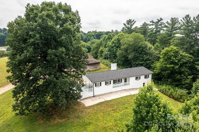 a house that is sitting in the grass with tress in the background
