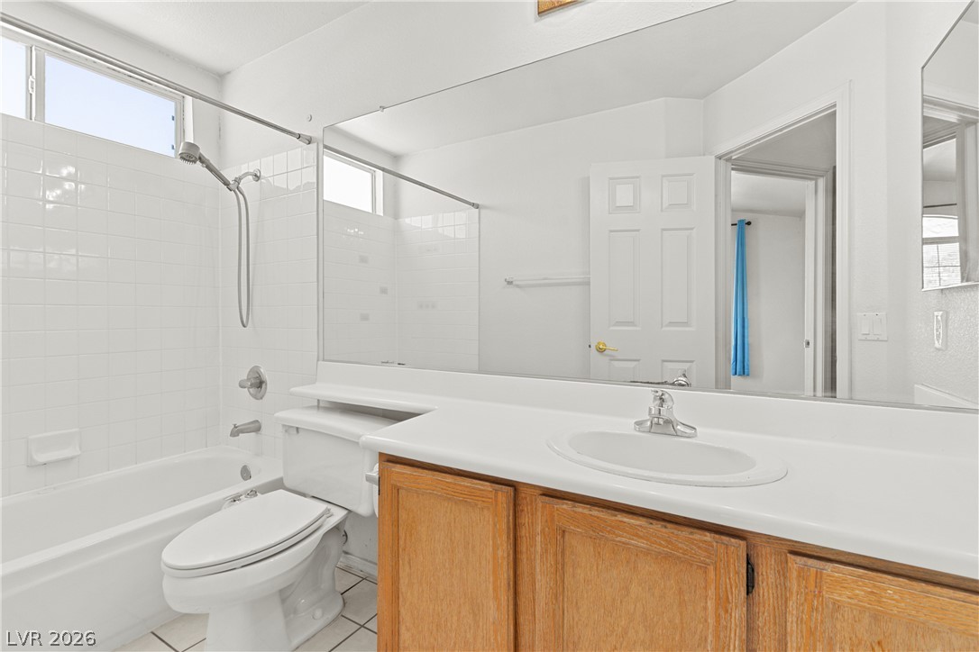 1815 Stablegate Avenue Henderson, NV 89012 - Photo 13 of 28 White tile walls and a bath/shower combination define this practical and tidy full bathroom.