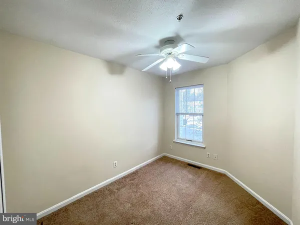 an empty room with a window and ceiling fan