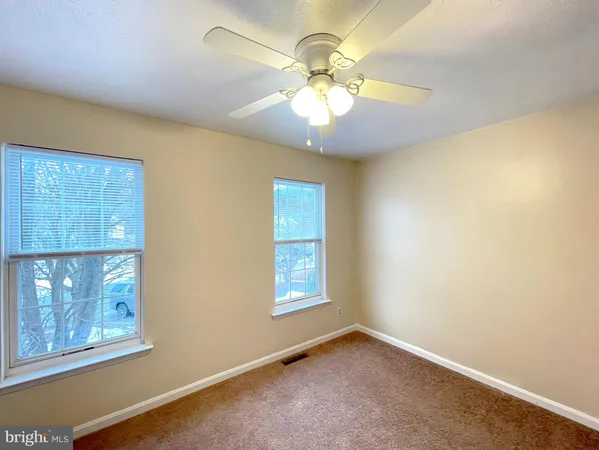 an empty room with windows and chandelier fan