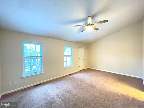 an empty room with windows and ceiling fan