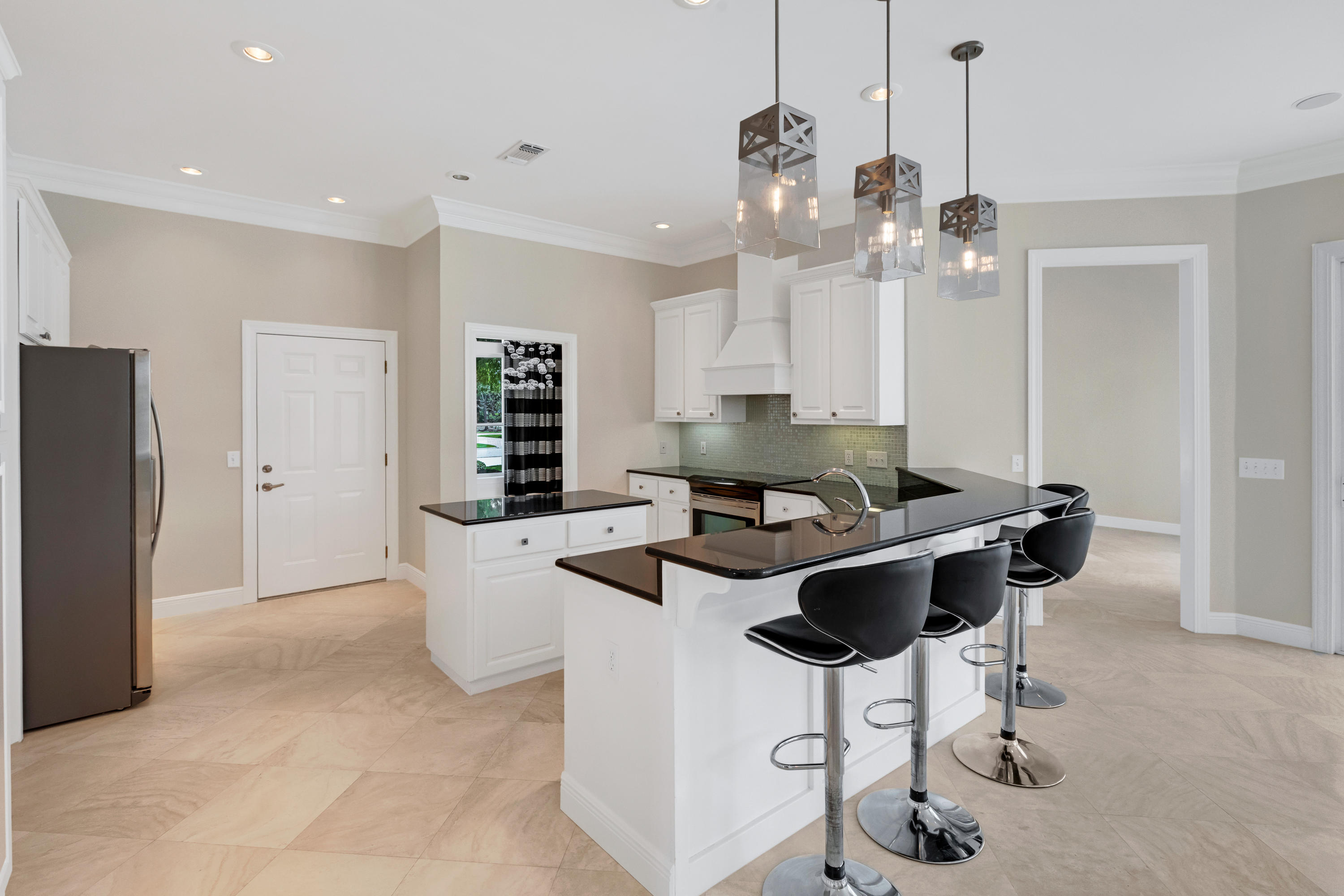 3606 Dragon's Ridge Road Panama City Beach, FL 32408 - Photo 12 of 49 a kitchen with stainless steel appliances kitchen island a table chairs in it and white cabinets