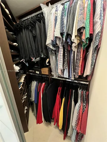 a view of walk in closet with clothes and shoes
