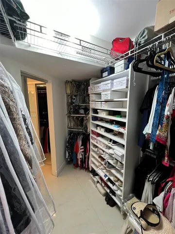 a view of walk in closet with clothes and shoes
