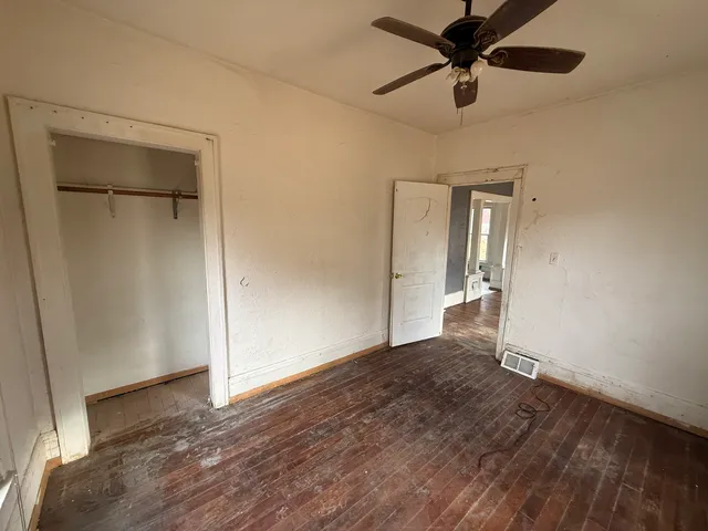 an empty room with wooden floor a ceiling fan