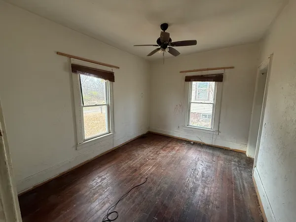 a view of empty room with wooden floor and fan