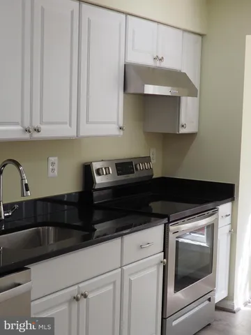 a kitchen with granite countertop white cabinets and black appliances
