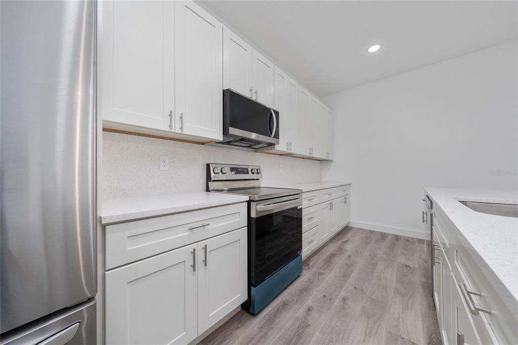8922 Southwest 135th Street Road Ocala, FL 34473 - Photo 12 of 44 a kitchen with white cabinets stainless steel appliances and wooden floor