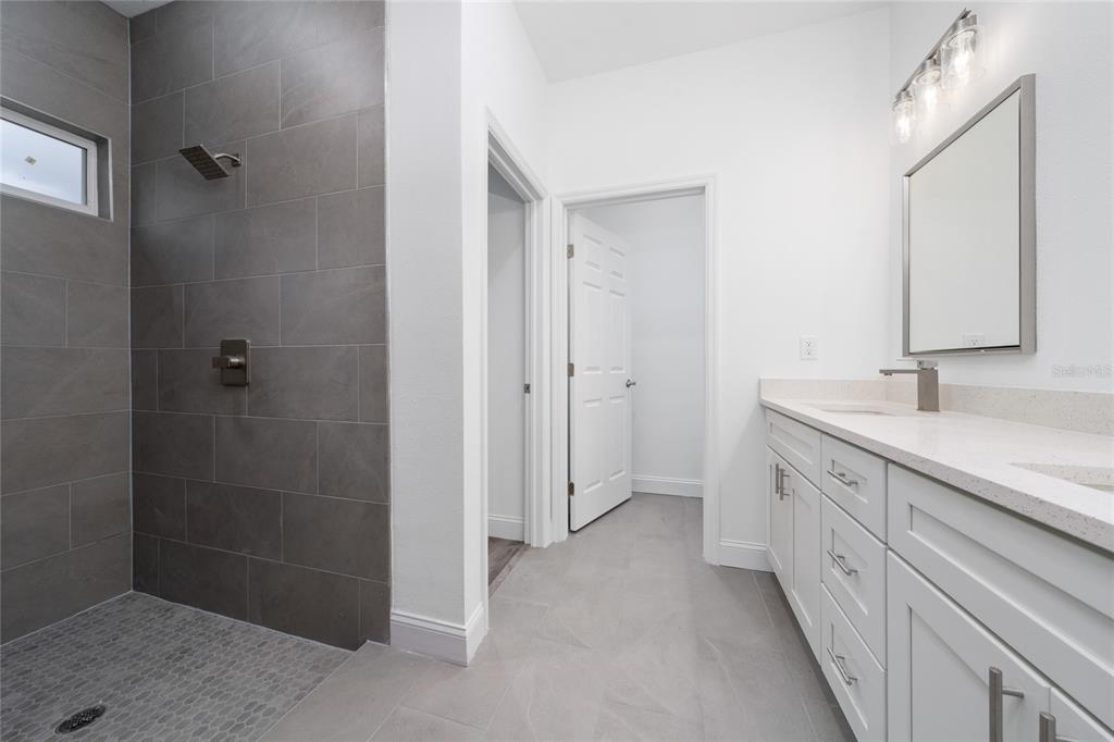 8922 Southwest 135th Street Road Ocala, FL 34473 - Photo 18 of 44 a spacious bathroom with a granite countertop sink a mirror and a shower