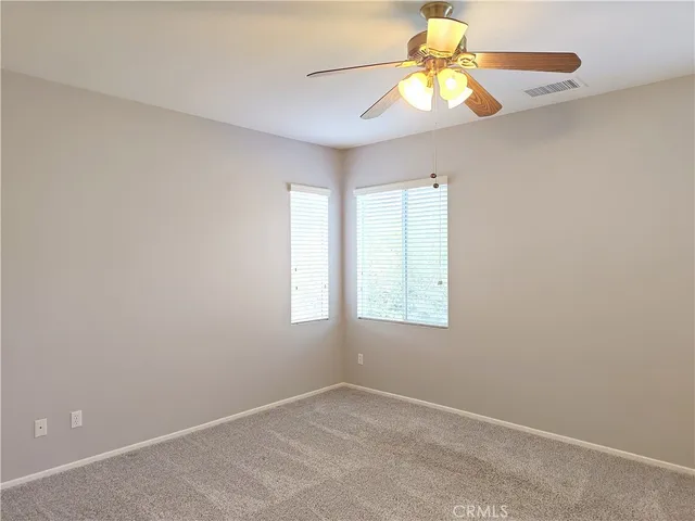 an empty room with window and chandelier fan
