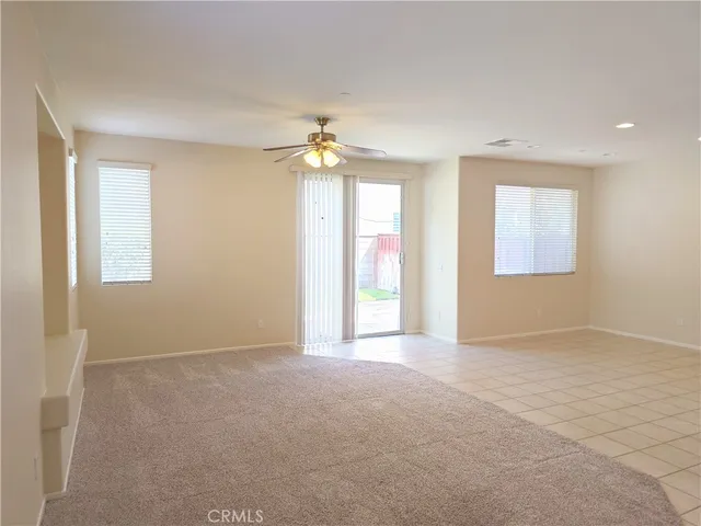 an empty room with windows and chandelier fan