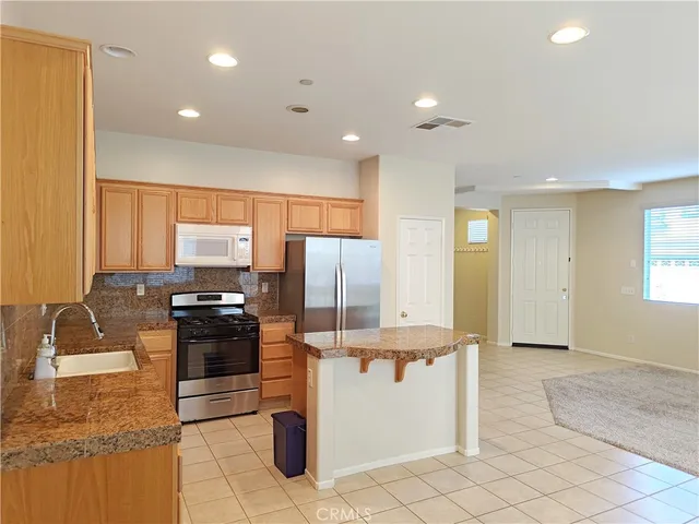 a kitchen with stainless steel appliances granite countertop a refrigerator a stove and a sink