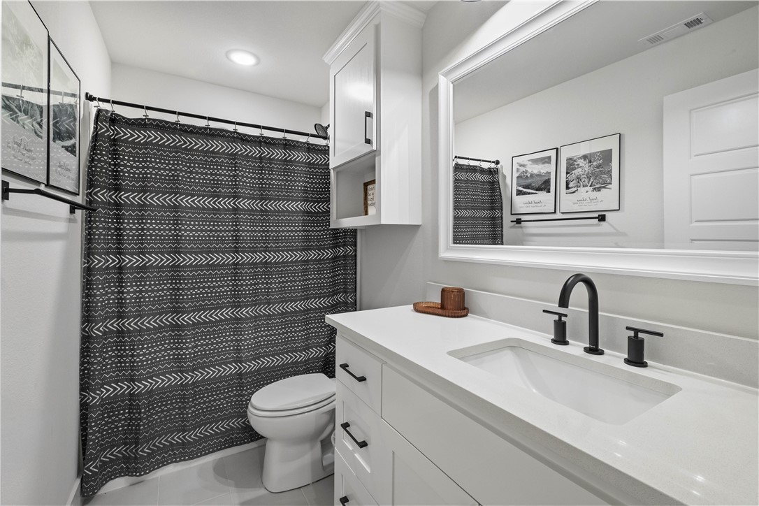 2055 Collins Drive Pea Ridge, AR 72751 - Photo 38 of 53 Bathroom featuring a white vanity with integrated sink, matte black fixtures, an expansive framed mirror, and built-in white cabinetry