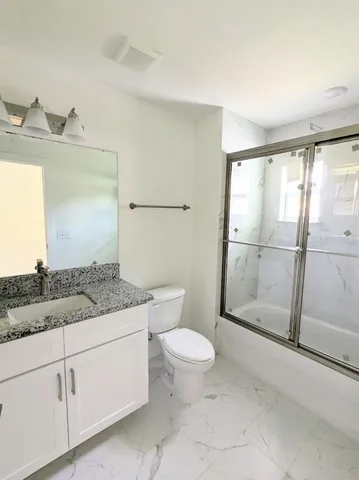 a bathroom with a granite countertop sink a mirror and a toilet