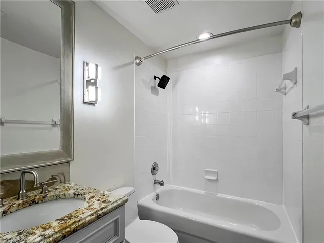 a bathroom with a granite countertop sink a toilet and shower