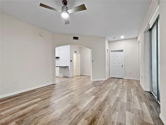 a view of empty room with wooden floor and fan