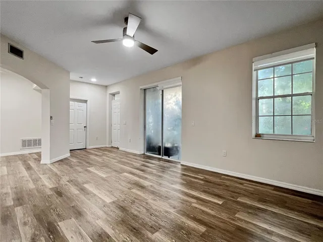 a view of empty room with wooden floor and fan