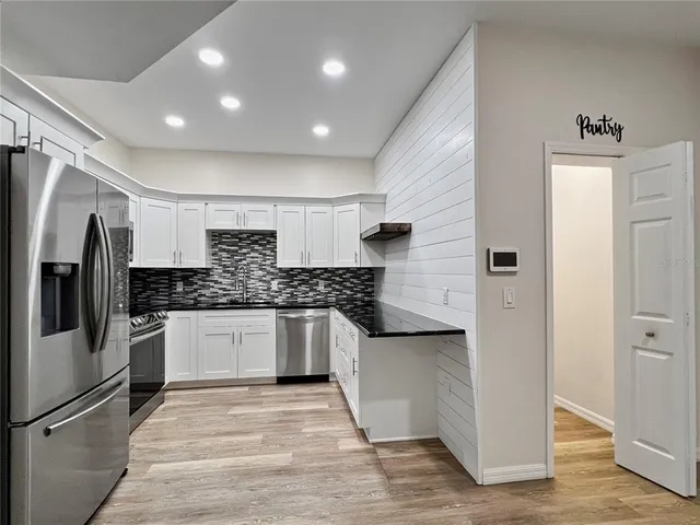 a large kitchen with stainless steel appliances granite countertop a refrigerator and a sink