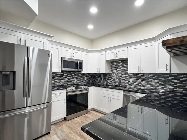 a kitchen with stainless steel appliances granite countertop a refrigerator sink stove microwave and cabinets