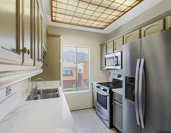 a kitchen with stainless steel appliances granite countertop a refrigerator a stove and a sink