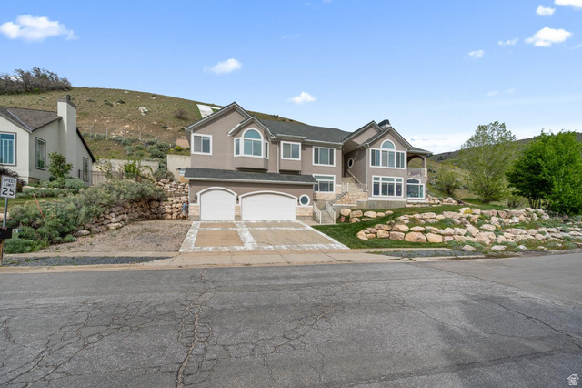 708 Eagle Rdg Drive Bountiful, UT 84010 - Photo 61 of 69 Multi-level residence featuring a gray exterior, arched garage doors, and a stone-accented driveway