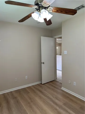 a view of an empty room and chandelier fan