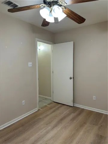 an empty room with wooden floor chandelier fan and closet area