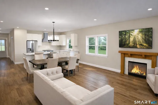 a living room with stainless steel appliances furniture a fireplace and a flat screen tv