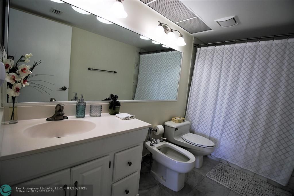 9341 Collins Avenue, Unit 1003 Surfside, FL 33154 - Photo 15 of 24 a bathroom with a granite countertop toilet sink and mirror