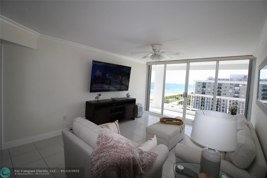 9341 Collins Avenue, Unit 1003 Surfside, FL 33154 - Photo 17 of 24 a living room with furniture a flat screen tv and a floor to ceiling window